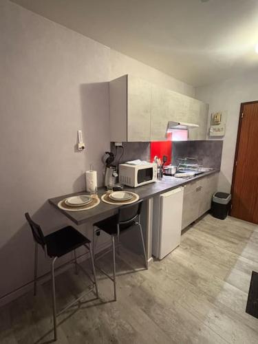 Il comprend une cuisine équipée d'une table avec deux chaises et d'un four micro-ondes. dans l'établissement Petit Nid Nature Et Douceurs, à Turckheim