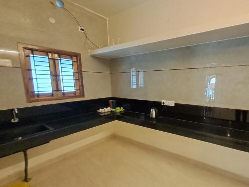a kitchen with black counter tops and a window at Jayam Home stay in Yercaud