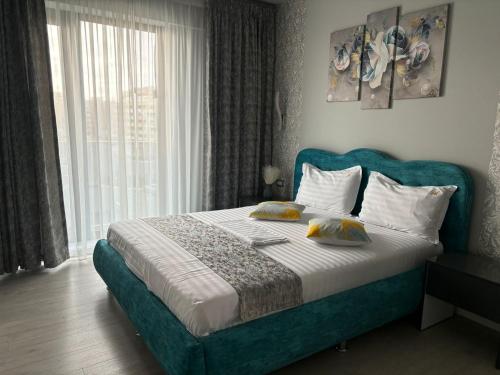 a bedroom with a bed with a blue headboard and a window at Alecsa 1 Luxury Residence in Mamaia