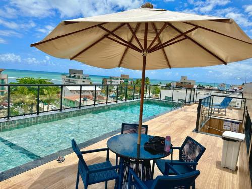 a table with an umbrella next to a swimming pool at Melhor localização Porto Galinhas 50M DO MAR E CENTRINHO - COM E SEM PISCINA PRIVATIVA Family Flats Porto de Galinhas in Porto De Galinhas