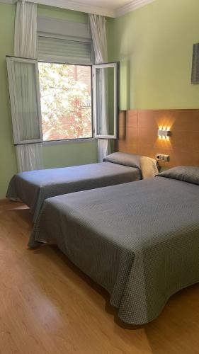 two beds in a room with a window at Hotel 4C Puerta Europa in Madrid