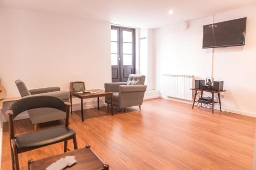 a living room with a couch and chairs and a flat screen tv at Republica Boutique Hostel in Porto