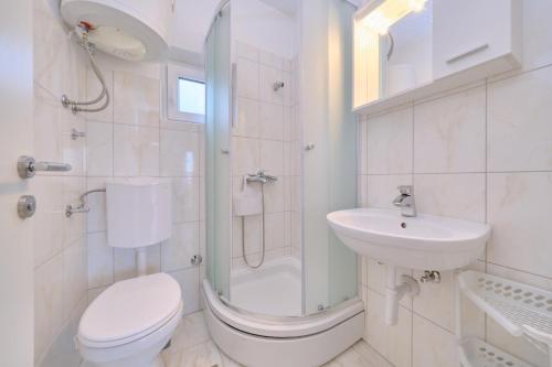 a bathroom with a toilet and a sink and a shower at Beachfront villa Mihovil with direct beach access in Kastel Stafilic
