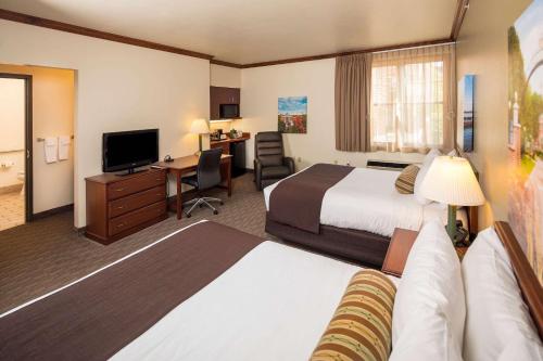 a hotel room with two beds and a desk at Kress Inn, an Ascend Collection Hotel in De Pere