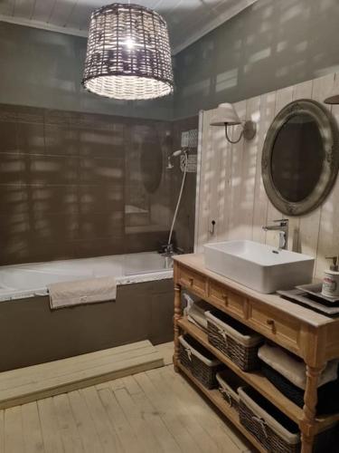 une salle de bain avec un lavabo, un miroir et une baignoire dans l'établissement Charmante maison ancienne avec cour, à Aleçon