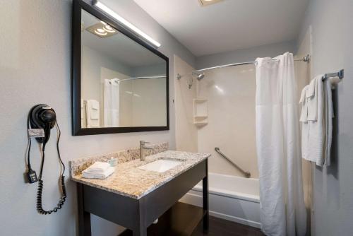 a bathroom with a sink and a mirror and a tub at Richland Riverfront Hotel, an Ascend Collection Hotel in Richland