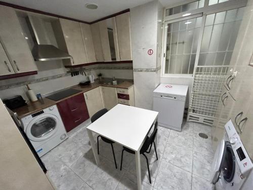a kitchen with a white table and a washing machine at Rooms Pontones in Madrid