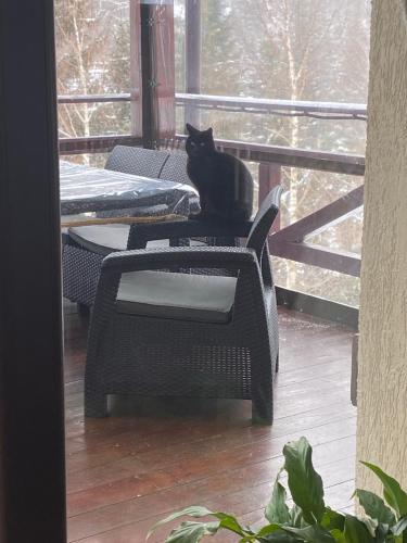 a black cat sitting on a table on a porch at Georgiy in Oryavchyk