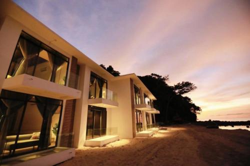 a building on the beach with the sunset in the background at Dolphin Bay Island Resort 海豚岛 in Kota Belud