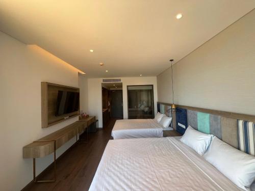 a hotel room with two beds and a flat screen tv at Apec Mandala Cham Bay Condotel Mui Ne in Mui Ne
