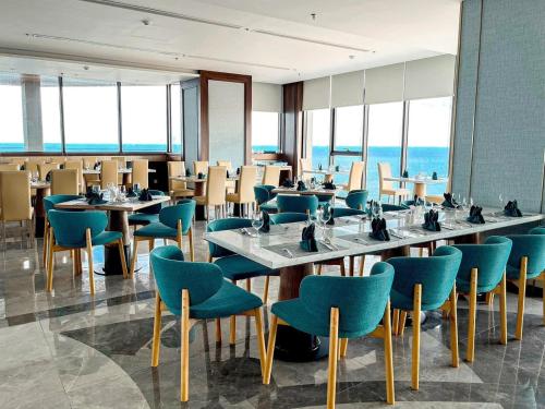 a dining room with tables and chairs and the ocean at Apec Mandala Cham Bay Condotel Mui Ne in Mui Ne
