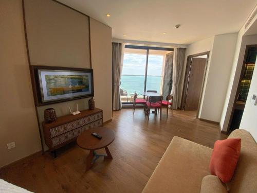 a living room with a couch and a tv and a table at Apec Mandala Cham Bay Condotel Mui Ne in Mui Ne