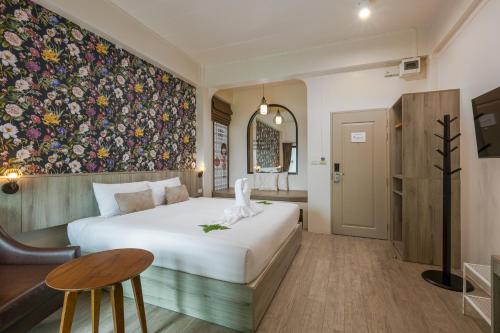 a bedroom with a large bed and a floral wall at Ang Pao Hotel Phuket in Phuket Town