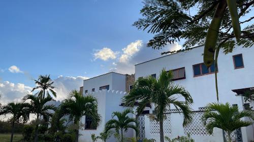 a white building with palm trees in front of it at Hayce Residence Ocean View Apartment in Kilifi