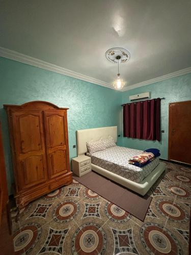 a small bedroom with a bed and a dresser at Résidence Fadloullah in Ouarzazate