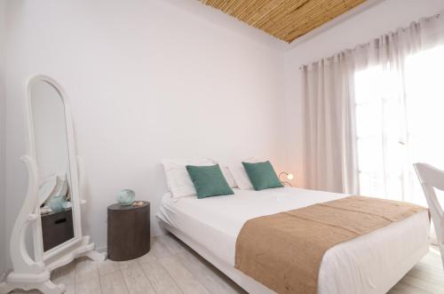 a white bedroom with a bed and a window at Thomais Studios in Naxos Chora