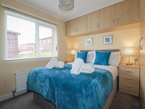 a bedroom with a large bed with blue and white sheets at Laurel Lodge in Tintagel