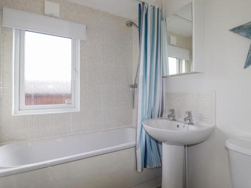 a bathroom with a sink and a tub and a window at Laurel Lodge in Tintagel