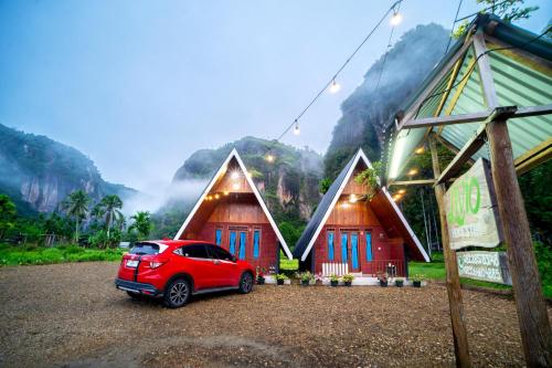 a red car parked in front of two huts at Livio Homestay in Andalas
