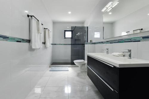 a white bathroom with a sink and a toilet at New Villa Luel 5 minutes from Palm Beach in Noord