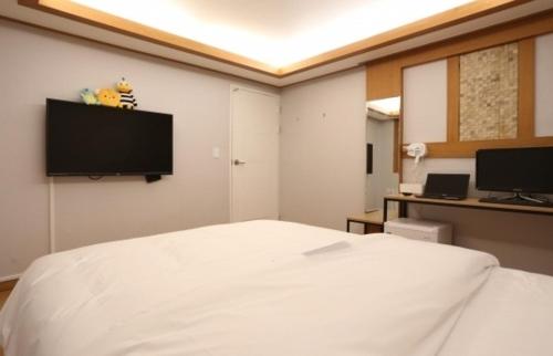 a bedroom with a white bed and a flat screen tv at 신림 유호텔 Seoul Sillim U Hotel - 고양이와 보드게임이 있는 힐링 숙소 in Seoul