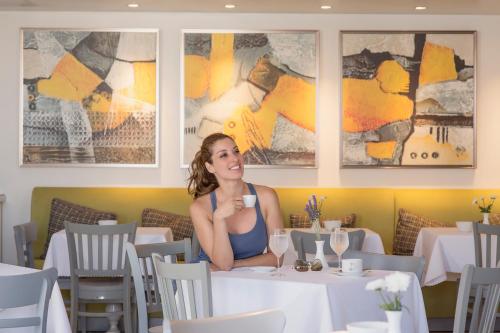 a woman sitting at a table in a restaurant at Kouros Art Hotel - Designed for Adults in Stelida