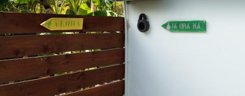 a white refrigerator with a sign on a wooden fence at Tehei Beach House Wifi AC Beachfront Sunset in Punaauia