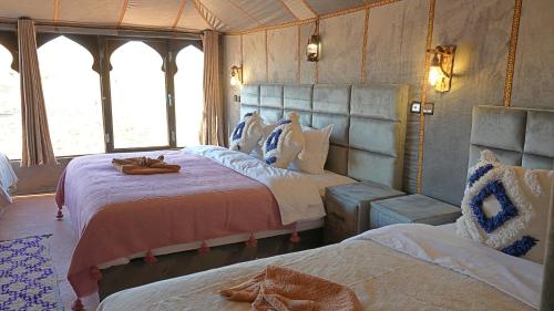 a bedroom with two beds in a room with windows at La Sultana Luxury Camp in Merzouga