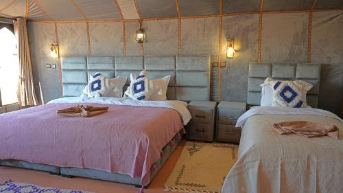 two beds in a room with two at La Sultana Luxury Camp in Merzouga