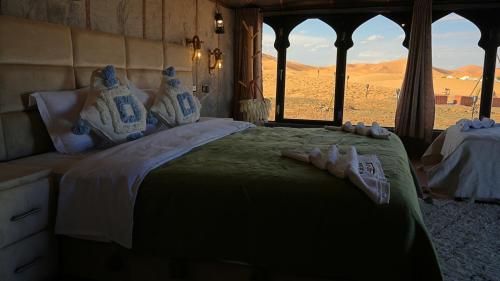 a bedroom with a bed with a view of the desert at La Sultana Luxury Camp in Merzouga