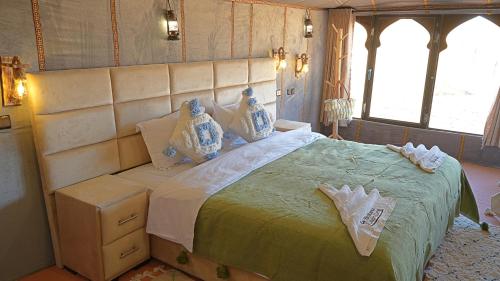 a bedroom with a large bed with a large headboard at La Sultana Luxury Camp in Merzouga