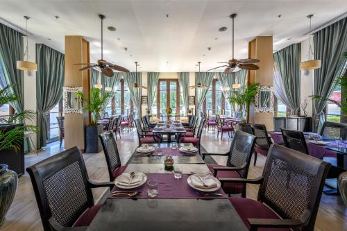 a dining room with tables and chairs and windows at Maikhao Dream Villa Resort and Spa, Maikhao Phuket in Mai Khao Beach