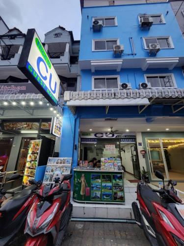a store with two scooters parked outside of a building at Nice to CU Guest house in Patong Beach