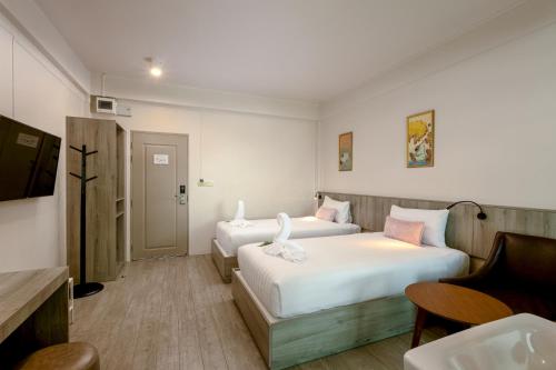 a hotel room with two beds and a television at Ang Pao Hotel Phuket in Phuket Town