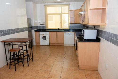 a kitchen with a sink and a table and a dishwasher at One Pavilion Luxury Serviced Apartments in Manama