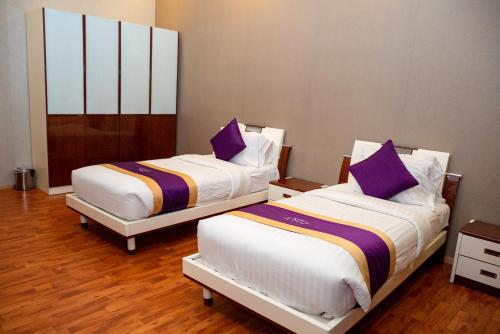 two beds in a room with purple pillows at One Pavilion Luxury Serviced Apartments in Manama