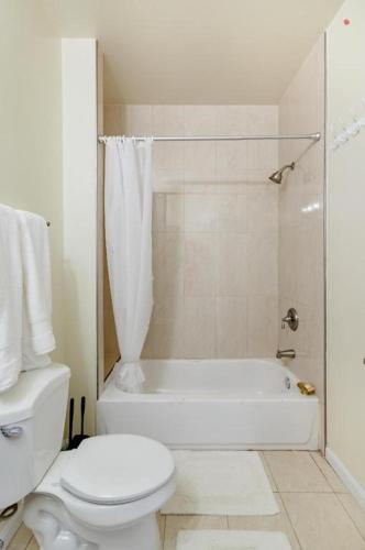 a white bathroom with a toilet and a shower at Luxury & Cherished Private Room in DC in Washington, D.C.
