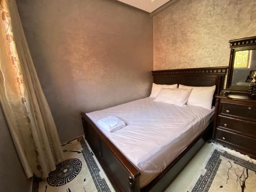 a bedroom with a bed with white sheets and a dresser at The Caring Corner in Agadir