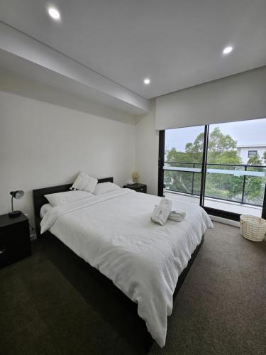 a white bedroom with a large bed and a large window at Rouse Hills TownCentre luxury accommodation in Kellyville