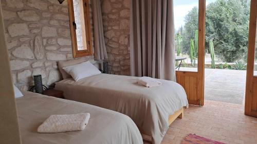 Dos camas en una habitación con pared de piedra. en Villa Coriandre, en Essaouira