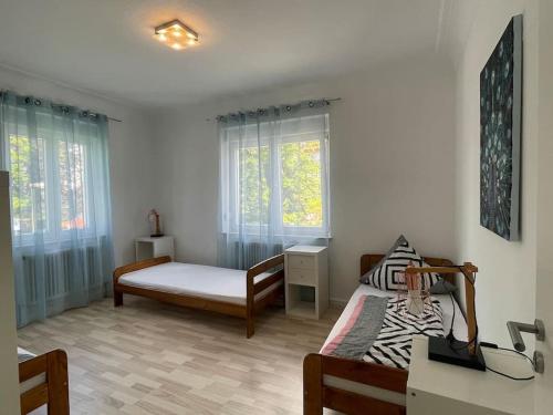 a bedroom with two beds and a desk and windows at Apart Mittelstation Nord Buxacher Straße 23 mit bikerental in Memmingen