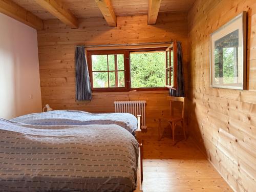 two beds in a wooden room with a window at Casa Seglias in Brigels