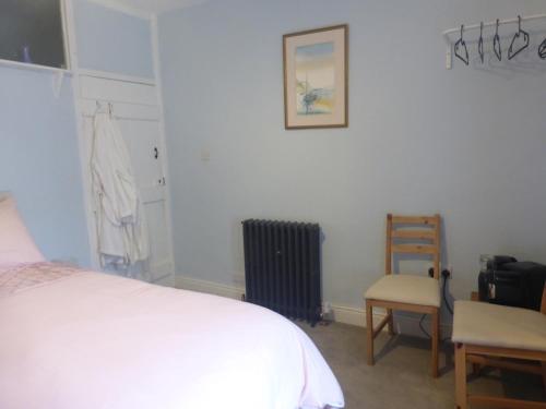 a bedroom with a white bed and a chair at Lyndale House in Bradwell