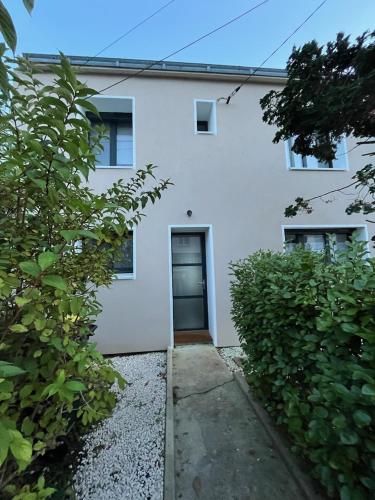 a white house with a door and two bushes at maison vue mer avec terrasse in Brest