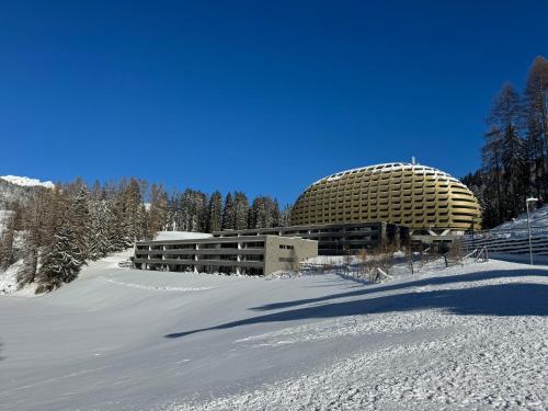 a building in the snow next to a snow covered field at Alpine Luxury Apartment Davos with Spa Access to 5 Star Hotel in Davos