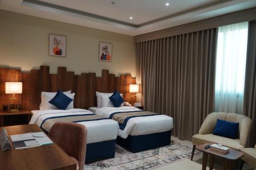 a hotel room with two beds and a desk at فندق ريان الجنادرية للشقق المخدومة Rayyan Al Janadriyah Hotel in Riyadh