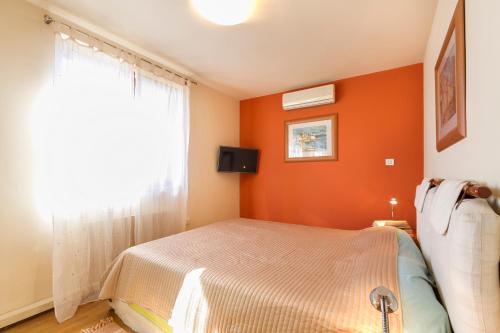 a bedroom with orange walls and a bed with a window at Villa Asi in Vrsar