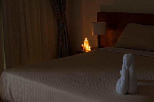 a bedroom with a bed with white sheets and a candle at Elaria Hotel Hurgada in Hurghada
