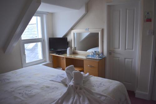 a bedroom with a bed and a desk with a mirror at Harrington Guest House in Newquay