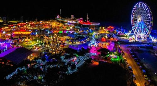 une vue aérienne sur un carnaval de nuit avec une roue ferris dans l'établissement Maison de vacances les pieds dans l'eau Port Leucate, à Leucate